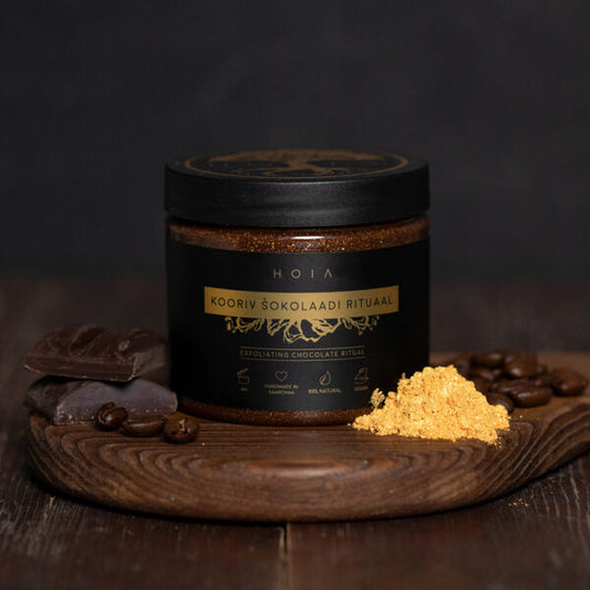 Exfoliating Chocolate Ritual Body Mask - A jar of brown powder and chocolate on a wooden board. Experience the ultimate pampering with this luxurious 200ML body mask infused with coffee, mint, and chocolate scents. Nourishing formula leaves skin silky soft and shimmering.