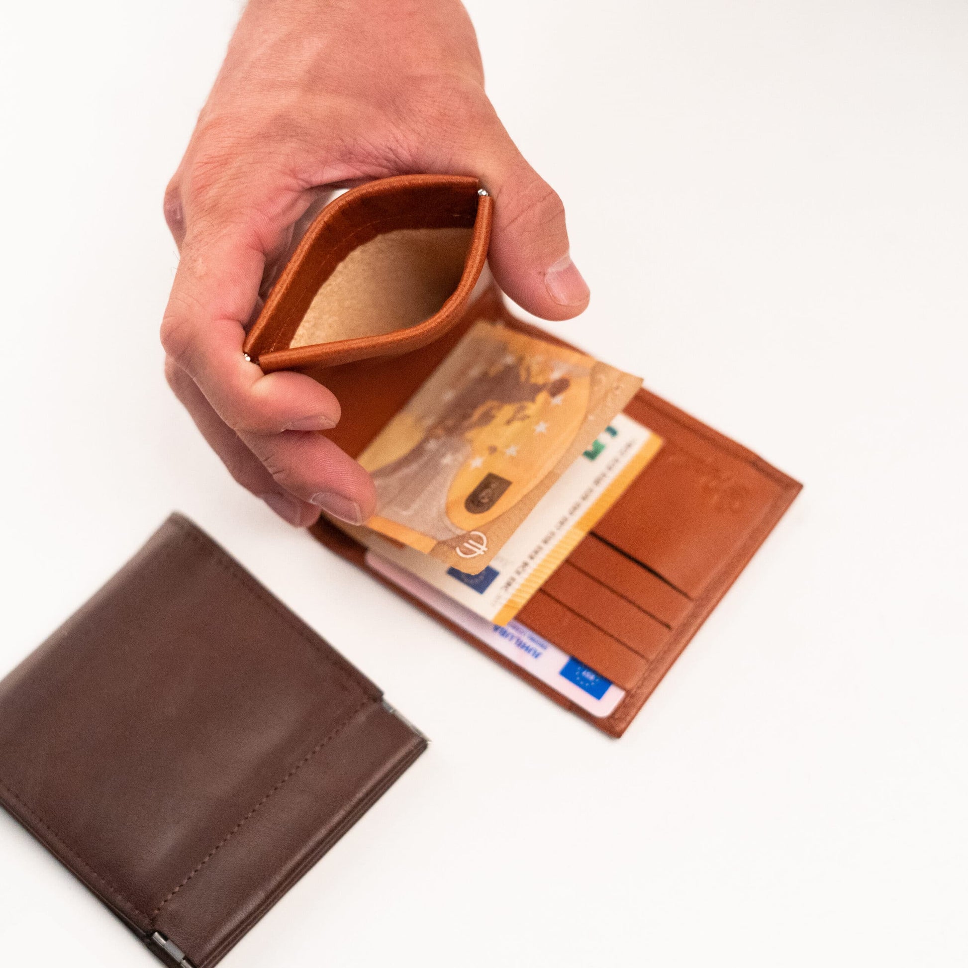 A hand holding a leather wallet with money clip and coin pouch, offering functionality and sophistication. Made from genuine leather in Europe, it includes 9 card slots, 1 ID window, and a metal clip for paper currency. Compact dimensions for easy carrying.