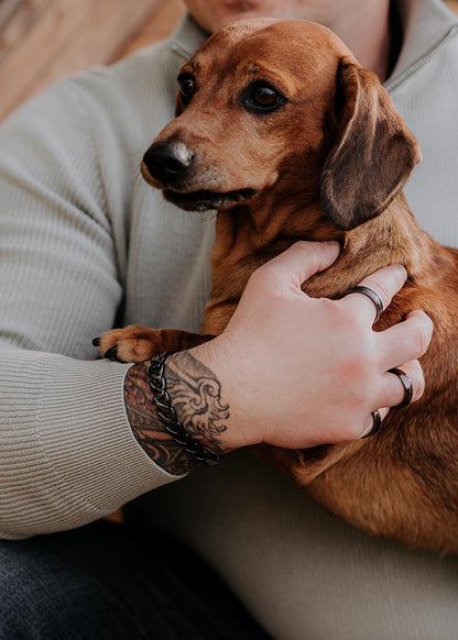 A man wearing the Rocco bracelet for Him, holding a dog. The black ceramic bracelet exudes sophistication and masculinity.