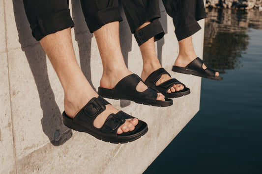 A group of people wearing Slip-On Leather Sandals with Adjustable Buckle - Black, providing exceptional comfort and timeless style.