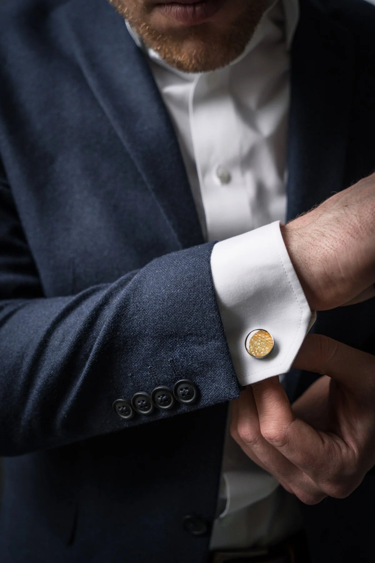 Man wearing a suit showcasing Cufflinks – Round – Yellow Trout Leather, highlighting unique fish scale patterns and stainless steel material.