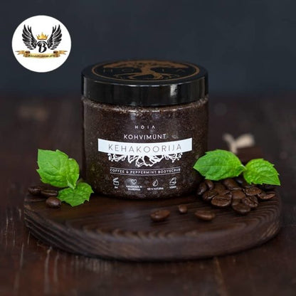 A jar of invigorating Body Scrub Coffee & Peppermint with black lid, coffee beans, and logo with wings and crown.