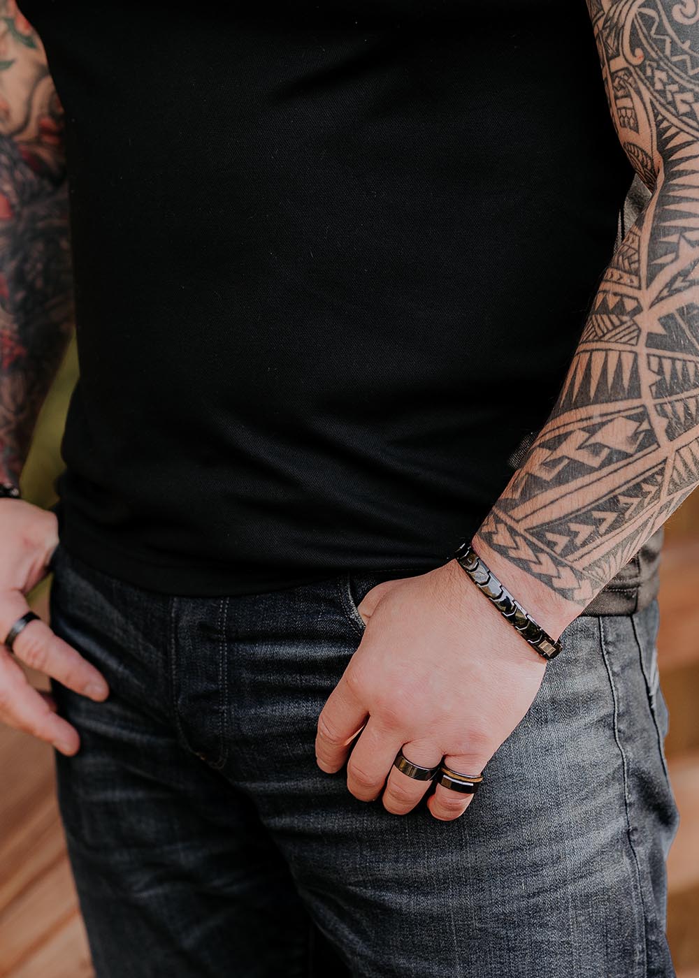 A man with tattoos wearing the Gent bracelet for Him, a sleek black ceramic bracelet with a stainless steel clasp.