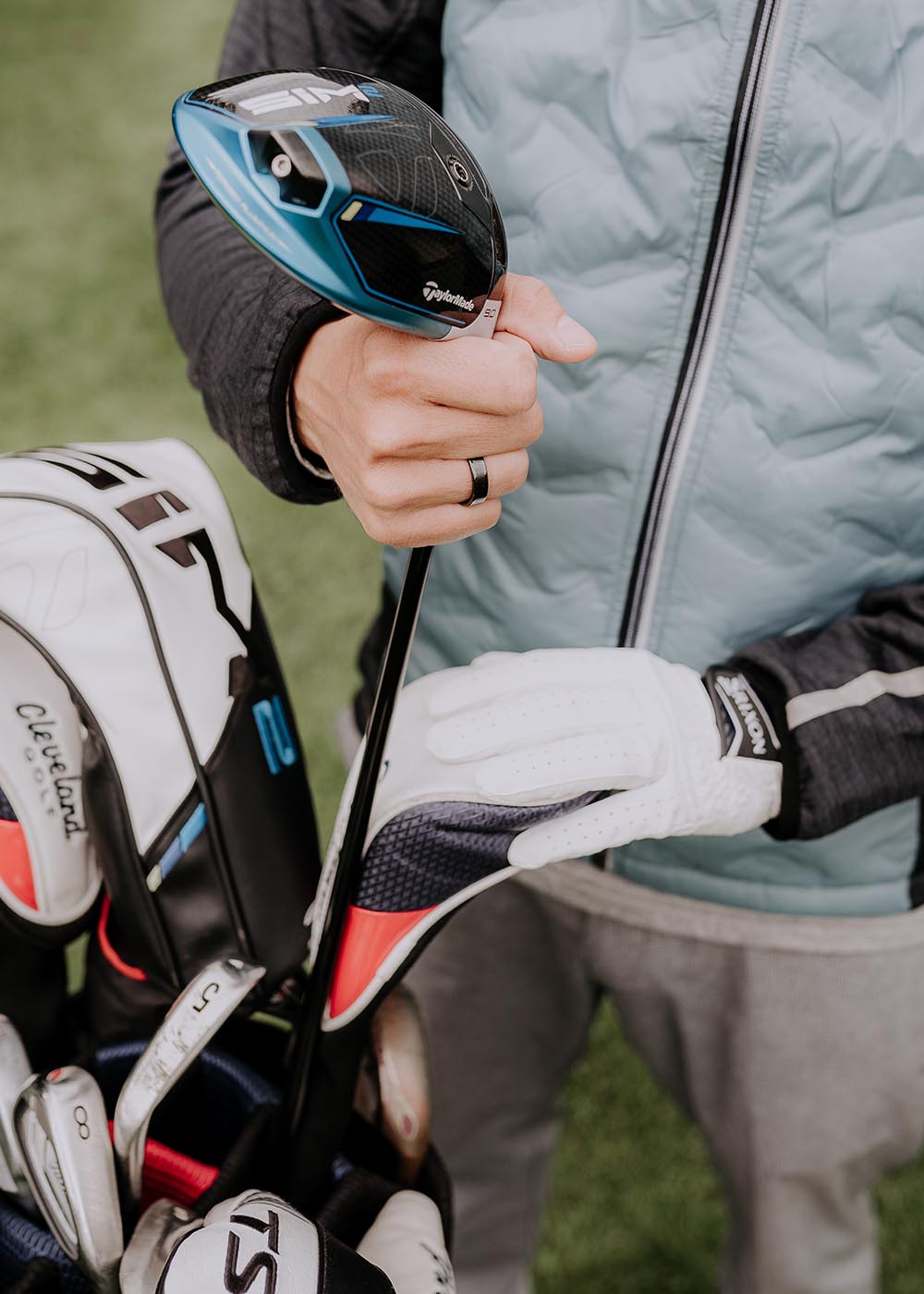 A person holding a golf club, wearing a Men's ring Leiw made of black ceramics.