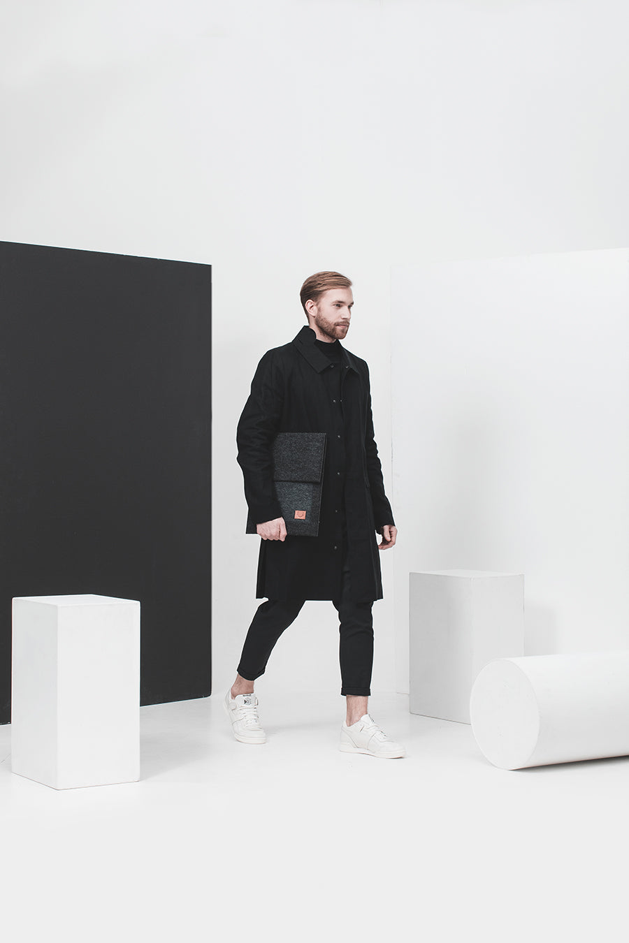 A man in a black coat holds a black folder, showcasing the Slim Fit Envelope Sleeve for Macbook Air & Pro - 13".