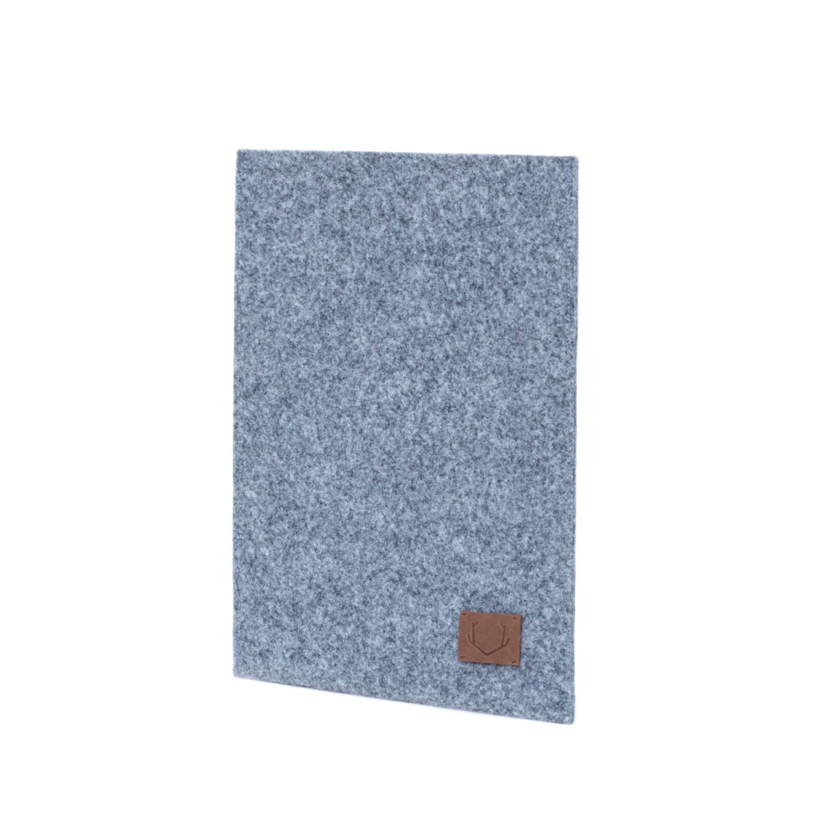 Slim fit sleeve for Macbook Air & Pro - 13': A grey rectangular object with a brown patch, close-up of a grey carpet, and a brown square with antlers carved on it. Crafted from durable felt, handmade in Europe, and designed for sustainability and weatherproof protection.