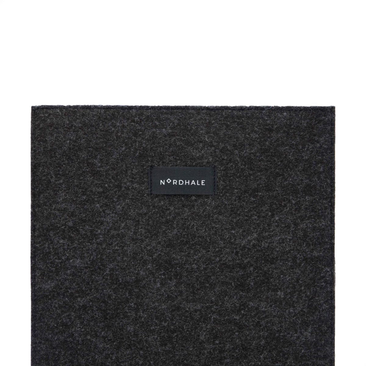 Slim fit sleeve for Macbook Air & Pro - 15" Black: A black square object with a black label featuring a logo. Perfect for professionals and students, it keeps your laptop safe and stylish. Made from durable felt, it offers functionality and style.