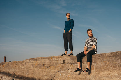 Two men sitting on a rock, wearing Light Slip-On Leather Sandals with Velcro Straps - Black from Men In Style.