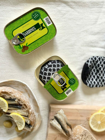 French Sardine Socks in a Can - size 35-46, presented alongside canned fish, creatively highlighting the novelty of compressed socks resembling sardines.